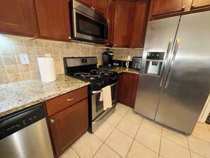 A kitchen with a stainless steel refrigerator, a microwave, a stove, and a dishwasher. - Spacious 3-Bedroom Apartment near New York City! (Harrison)