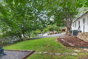 A residential backyard with a lawn, stone pathway, and a white house. - Charlotte Escape | Near NoDa & Plaza Midwood (Charlotte)