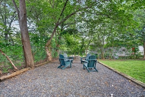 An outdoor seating area with two Adirondack chairs and a fire pit. - Belmont Duplex | Shops, Dining & Entertainment (Charlotte)