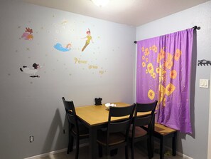 A dining area with a table and chairs, a wall with star decals and a 'Never grow up' message, and a purple curtain with a floral pattern. - Charming 2-bedroom apartment with AC in lively Phoenix (Phoenix)