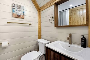 Een badkamer met een houten wastafelmeubel, toilet en spiegel.