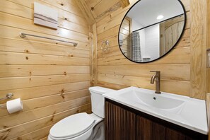 Een betegelde badkamer met toilet, wastafel en spiegel.