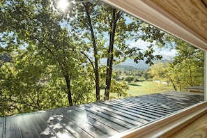 A room with a large window overlooking a forested area with trees and a view of the landscape. - 3 Cabin Rental on Private Farm, 15 mins from Chatt (Chattanooga)