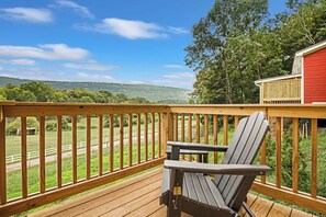 A wooden deck with a view of a green landscape and a red building. - 3 Cabin Rental on Private Farm, 15 mins from Chatt (Chattanooga)