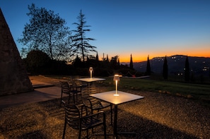 An outdoor seating area with tables and chairs, overlooking a mountainous landscape during sunset. - New Listing (Volterra (PI))