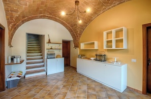 A kitchen with a brick archway, white cabinetry, and a tiled floor. - New Listing (Volterra (PI))