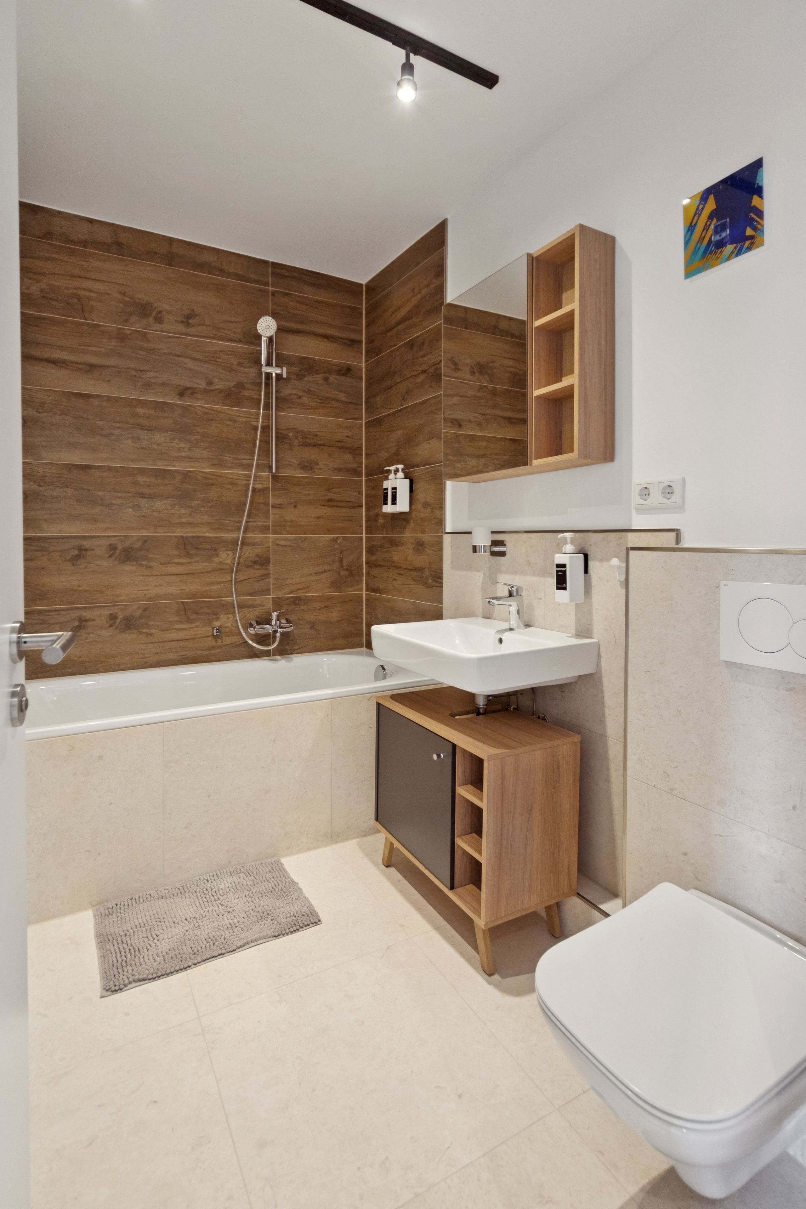 Ein modernes Badezimmer mit einer Holzwand, einer Badewanne, einem Waschbecken und einer Toilette.