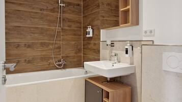 Ein modernes Badezimmer mit einer Holzwand, einer Badewanne, einem Waschbecken und einer Toilette.