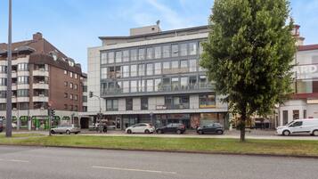 Ein mehrgeschossiges Gebäude mit moderner Fassade, mit einem Ladenlokal im Erdgeschoss, auf dem die Schilder 'Biffar Studio' und 'ParfumKönig' sichtbar sind.