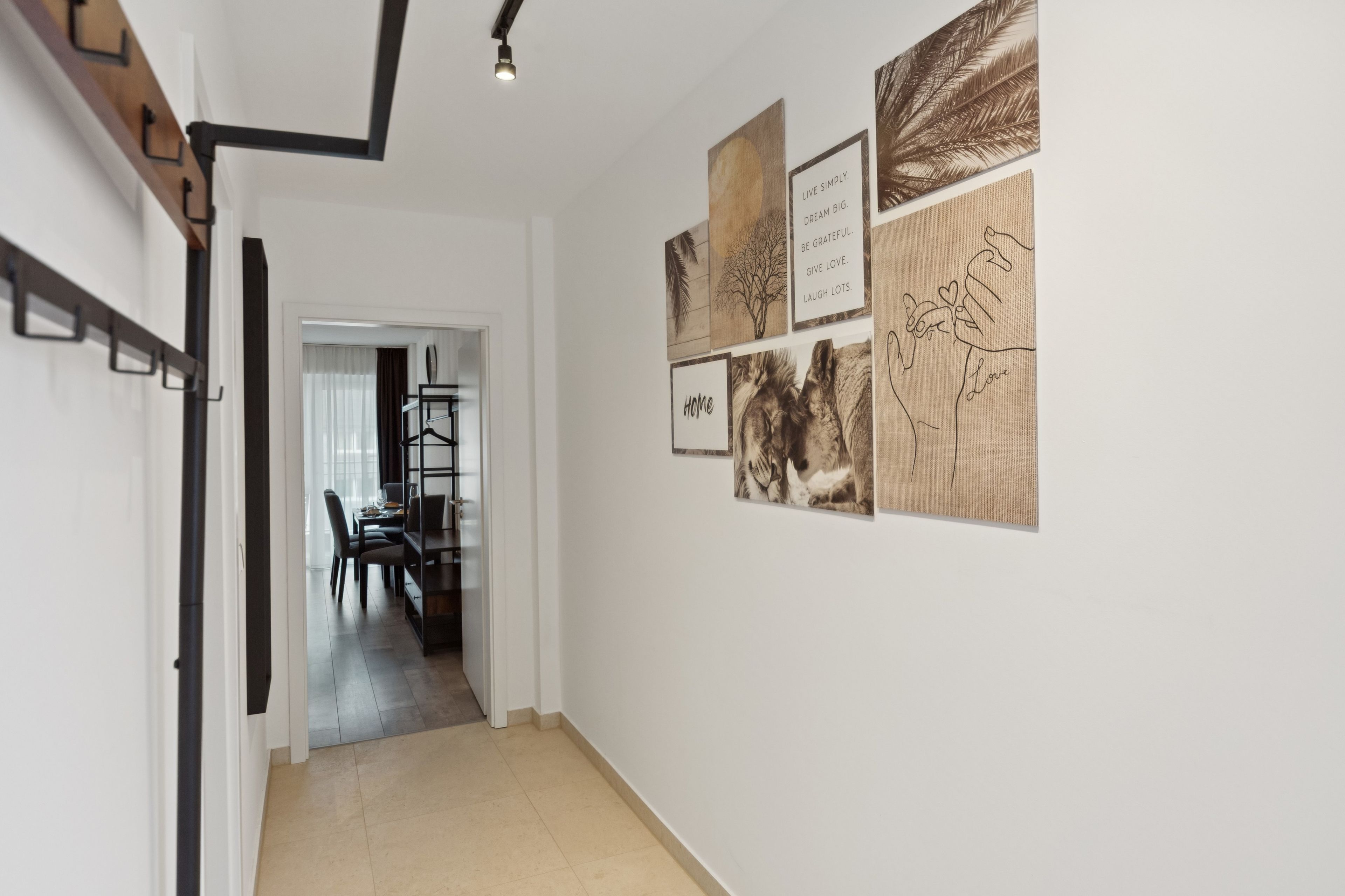 A hallway with a dining area visible through an open door, featuring a table and chairs.