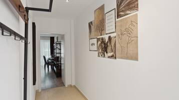 A hallway with a dining area visible through an open door, featuring a table and chairs.