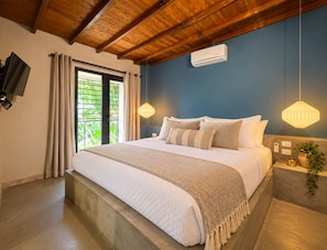 A bedroom with a large bed, a television on the wall, and a window with curtains. - New Listing (Medellín)