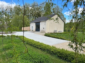 A stone building with a dark roof, a paved driveway, and a well-maintained garden. - New Listing (Champigny-sur-Veude)