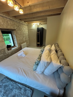 A bedroom with a large bed, a wardrobe, a small window, and a wooden ceiling. - New Listing (Champigny-sur-Veude)