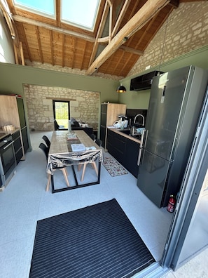 A modern kitchen with a large refrigerator, wooden beams, and a stone wall. - New Listing (Champigny-sur-Veude)
