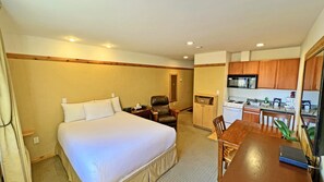 A hotel room with a bed, a desk, a chair, a kitchenette, and a bathroom. - Elizabeth Lake Lodge (Cranbrook)