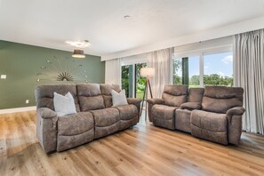 A living room with two reclining sofas, a floor lamp, and a ceiling light fixture. - Tranquil Golf Themed Getaway with Lake View! (Haines City)