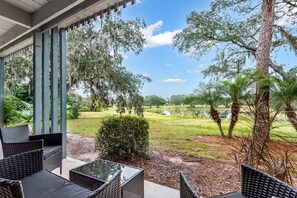 An outdoor patio with wicker furniture, a view of a golf course, and a pond. - Tranquil Golf Themed Getaway with Lake View! (Haines City)