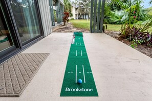 Une table de jeu de palet avec une surface verte et portant l’inscription « Brookstone », installée à l’extérieur sur un sol en béton, avec un bâtiment en arrière-plan.