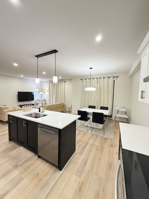 A modern kitchen with a central island, black cabinets, and a dining area with a table and chairs.