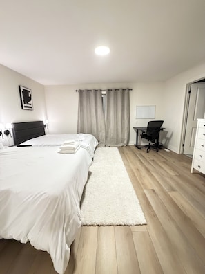Hotellihuone, jossa on sänky, työpöytä, tuoli, lipasto ja ikkuna, jossa on verhot.