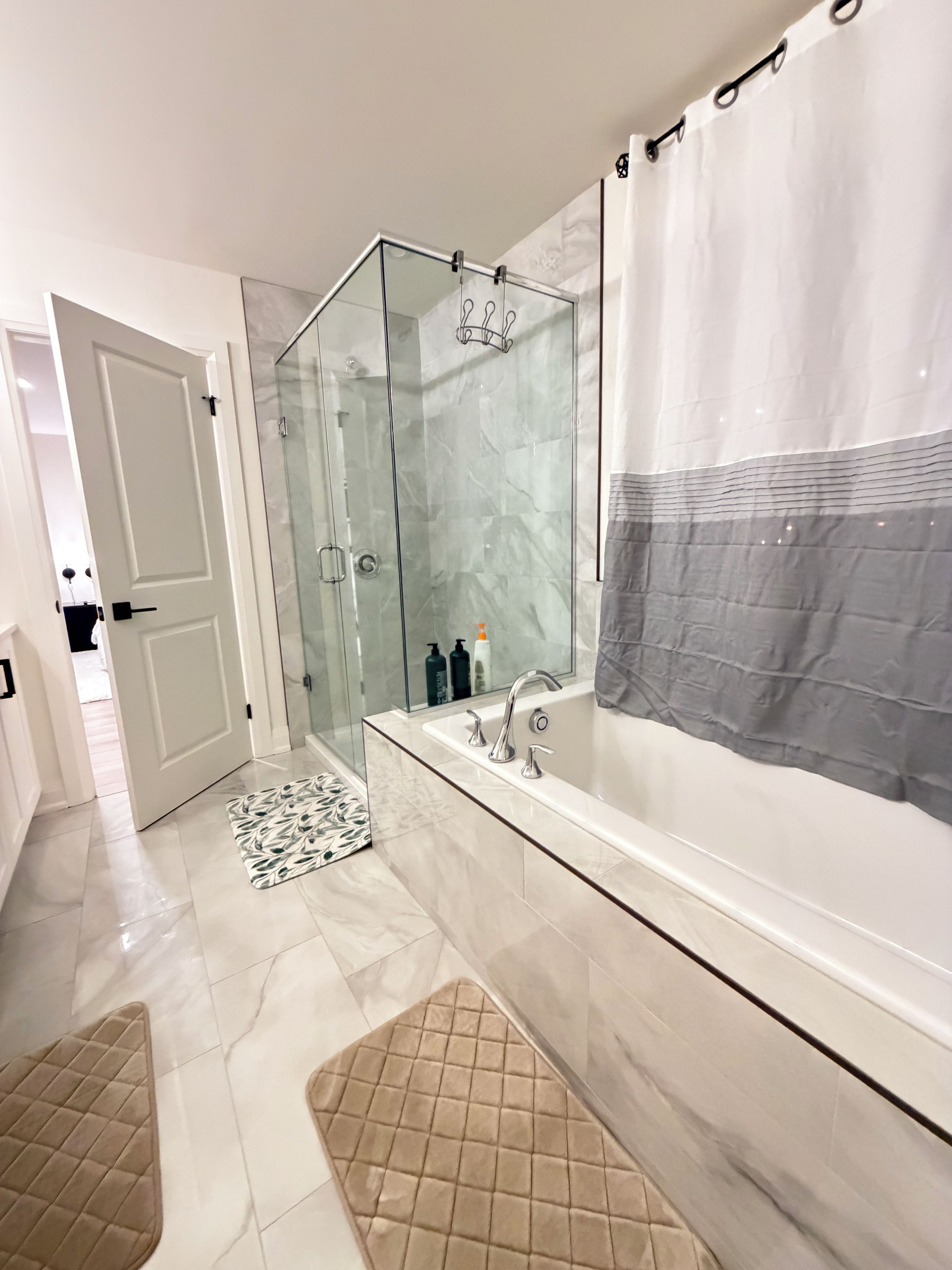 Une salle de bain moderne avec une douche à l’italienne, une grande baignoire et une douche séparée.