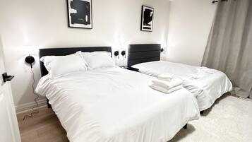A hotel room with two beds, a white carpet, and a wooden floor.