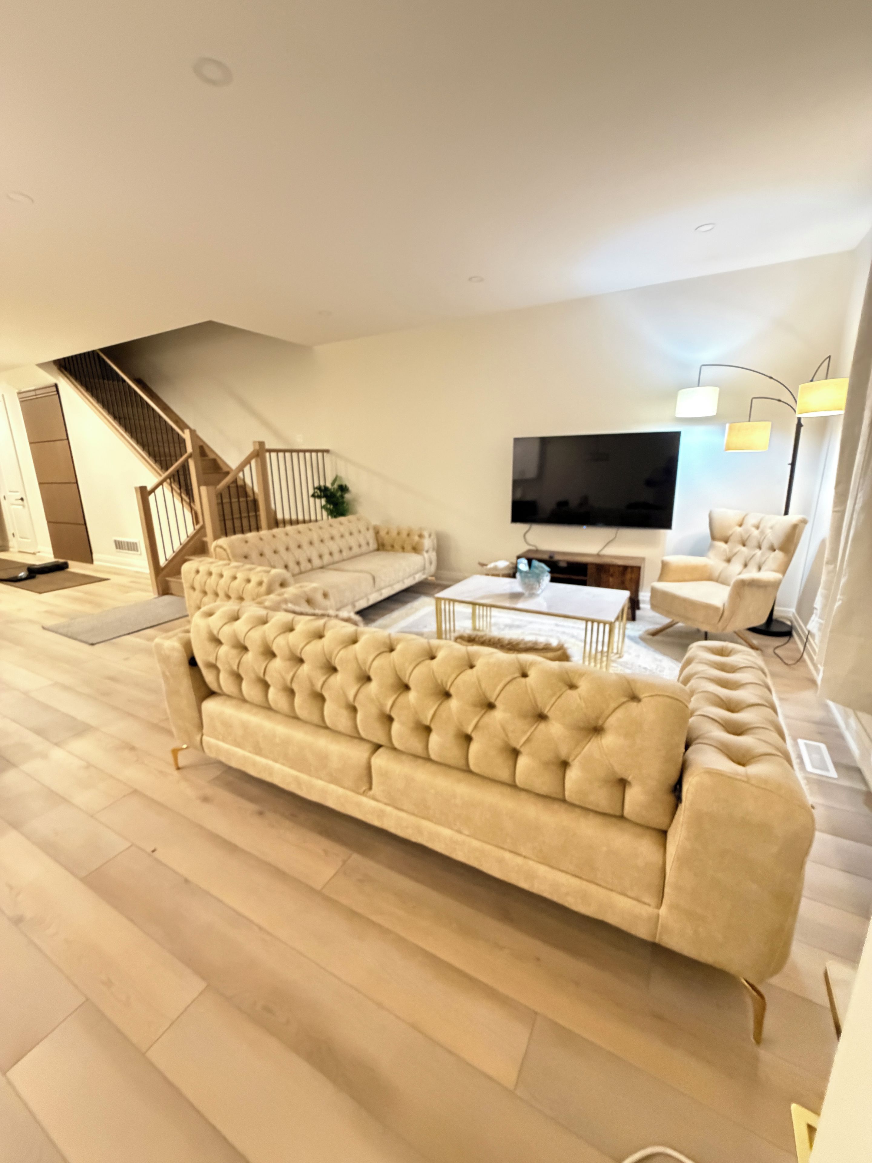 Un salon moderne avec un grand canapé beige, une table basse et un téléviseur à écran plat fixé au mur.