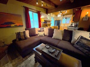 A cozy living room with a sectional sofa, a coffee table, and a painting on the wall. - 65 Creekside House | Private Deck On The Water (Sedona)