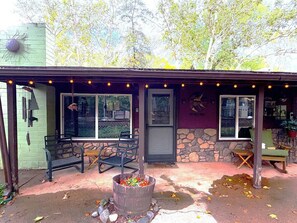 A building with a porch, outdoor seating, and a fire pit. - 65 Creekside House | Private Deck On The Water (Sedona)