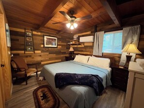 A cozy bedroom with a bed, a chair, a ceiling fan, and a window with curtains. - 65 Creekside House | Private Deck On The Water (Sedona)
