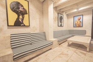A room with striped benches and a patterned table, with artwork on the walls. - Luxury 8 Bedroom Mansion in Old City Best Location (Cartagena de Indias)