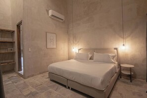 A bedroom with a bed, bedside table, and an air conditioning unit. - Luxury 8 Bedroom Mansion in Old City Best Location (Cartagena de Indias)