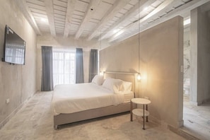 Ein Schlafzimmer mit einem Bett, einem Nachttisch und einem an der Wand befestigten Fernseher.