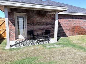 A brick house with a covered porch, two chairs, and a door. - Midland Modern 3BR Home (Midland)