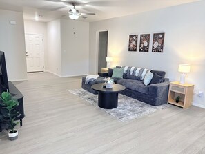 A modern living room with a sofa, coffee table, and a ceiling fan. - Midland Modern 3BR Home (Midland)