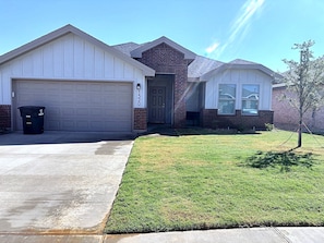 A residential house with a garage, a front door, and a well-maintained lawn. - Midland Modern 3BR Home (Midland)