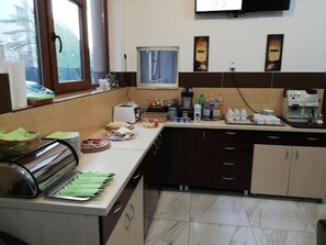 Una cocina con espacio tipo bufé, que incluye un tostador, una cafetera y diversos alimentos.