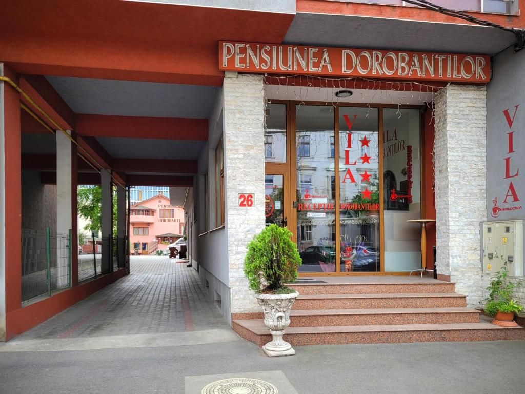 The entrance to a building with a sign reading 'PENSIUNEA DOROBANTILOR' and a number '26' above the door.