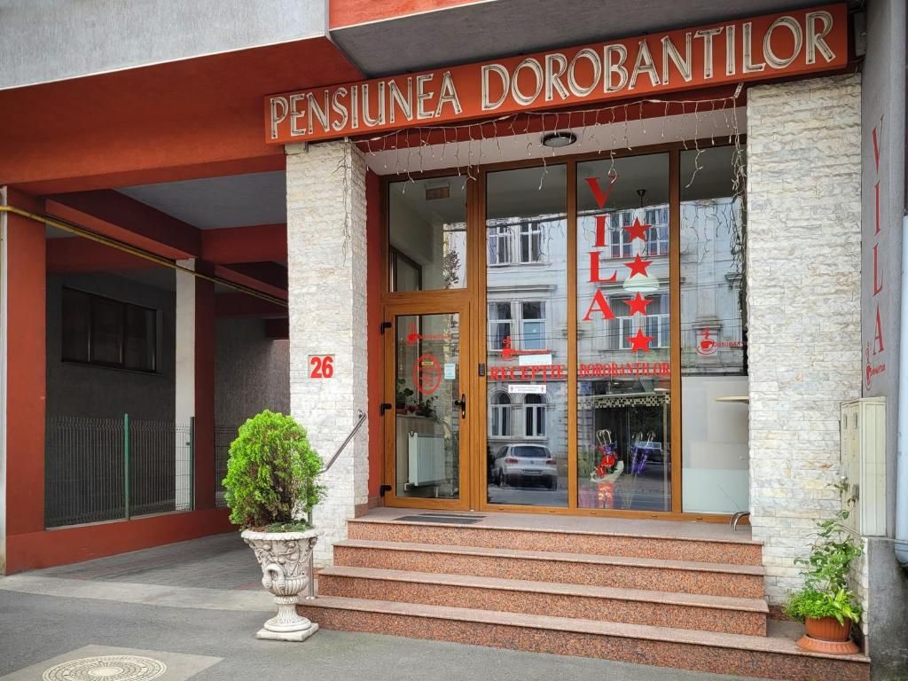 A entrada de um edifício com uma placa que diz 'PENSIUNEA DOROBANTILOR' e o número '26' na parede.