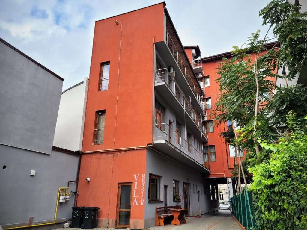 A multi-story building with balconies, a visible entrance, and a small outdoor seating area.