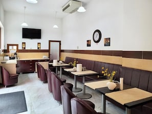 Um restaurante com cabines e mesas, um relógio e uma televisão na parede.