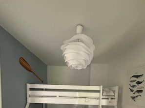 Een stapelbed met een wit hoofdbord en een plafondlamp.