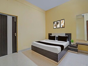 A modern bedroom with a bed, bedside tables, a mirror, and artwork on the wall. - Deluxe Sri Krishna Palace (Bhubaneshwar)