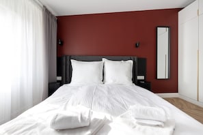 A hotel room with a bed, white linens, a dark headboard, a mirror, and a red accent wall. - Armas 9 Szlachetne Bordo z Sypialni (Bydgoszcz)