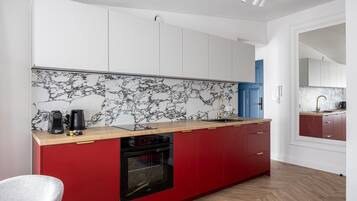 A modern kitchen with a marble backsplash, red cabinetry, and a built-in oven.