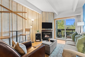 A living room with a fireplace, a sofa, a television, and a view of the outdoors. - Tmc304f2 (Frisco)