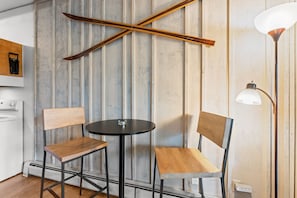 A room with a wooden-framed wall, a round table with two chairs, a floor lamp, and a washing machine. - Tmc304f2 (Frisco)