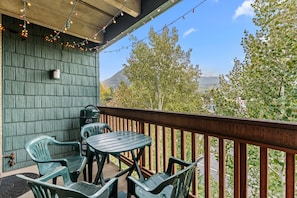 A balcony with a wooden railing, a table, and two chairs. - Tmc304f2 (Frisco)