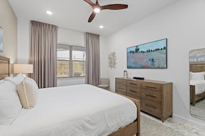 A bedroom with a bed, a dresser, a ceiling fan, a window with blinds, and a painting on the wall. - 6BR Themed Villa Private Pool Near Universal (Orlando)
